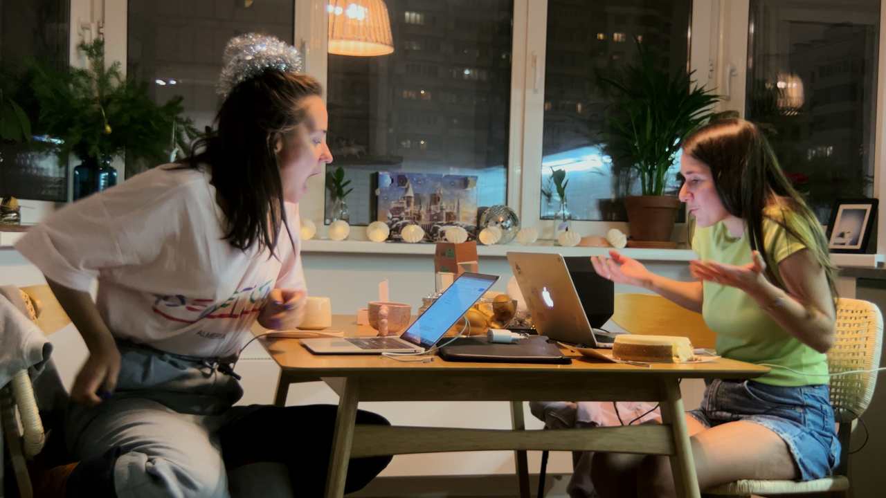 two woman sitting at a table in front of laptops